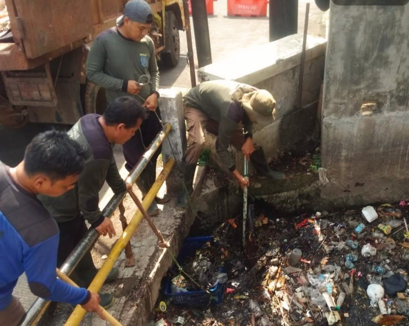 Petugas Satgas Dinas PUPR Depok sedang membersihkan sampah di saluran air di Cinere.