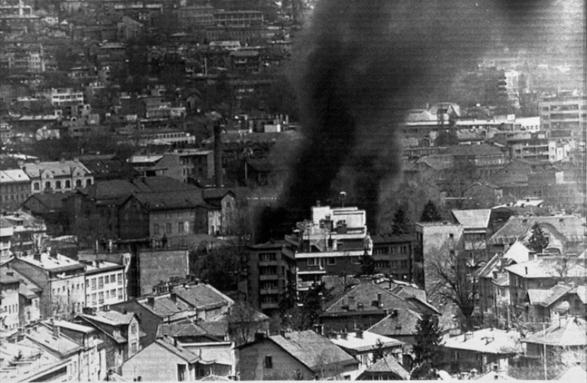 Dalam foto dari 22 April 1992, asap mengepul dari sebuah bangunan di pusat kota Sarajevo setelah serangan mortir Serbia selama perang di Bosnia dan Herzegovina [File: AP Photo/Tanjug/H Delich]