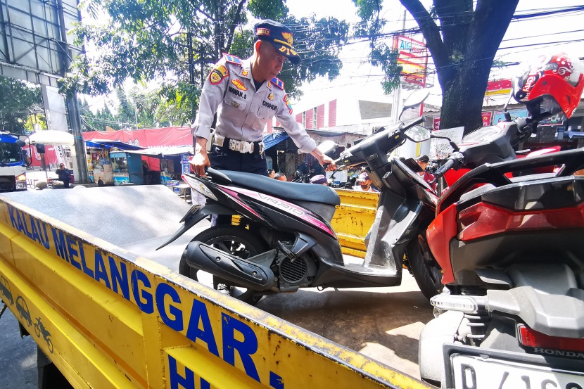 Petugas Dinas Perhubungan menaikkan sepeda motor yang terparkir di badan jalan Jl Purnawarman Bandung, Senin (15/7/2024). (Foto: Yogi Ardhi/KangJepret)