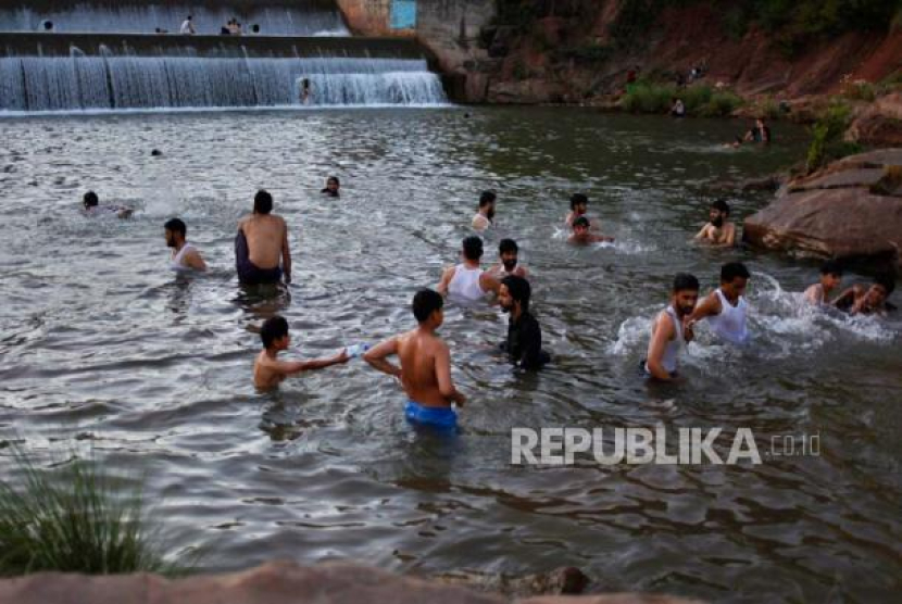 Warga mendinginkan tubuh di sungai ketika suhu mencapai 40 derajat celcius di Islamabad, Pakistan, Rabu (27/5/2020). Foto: AP/Anjum Naveed