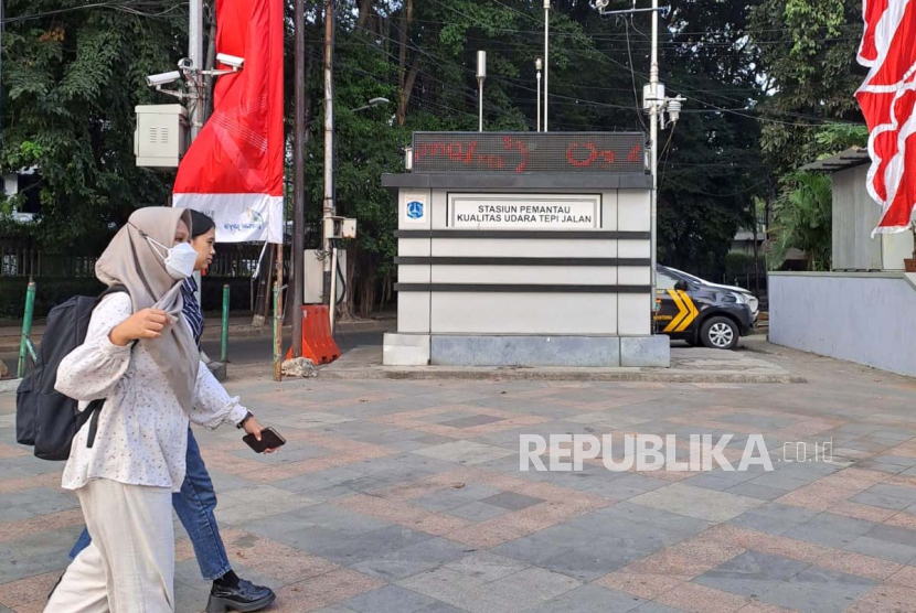 Warga melintasi stasiun pemantau kualitas udara tepi jalan yang dipasang di Bundaran HI, Jakarta Pusat, Selasa (15/8/2023) (foto: eva rianti/republika).