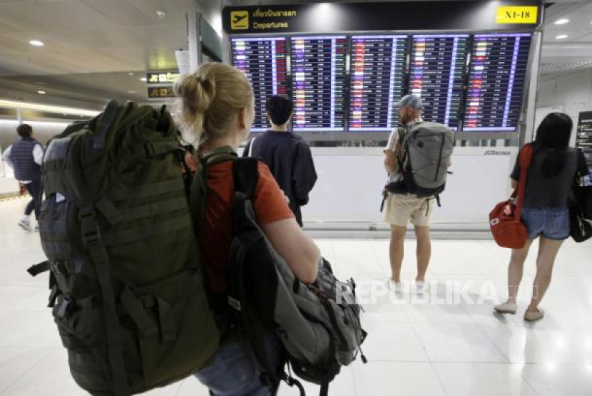 Turis asing memeriksa papan informasi penerbangan di terminal penumpang di Bandara Internasional Suvarnabhumi di provinsi Samut Prakan, Thailand, Kamis (16/2/2023). (EPA-EFE/NARONG SANGNAK)