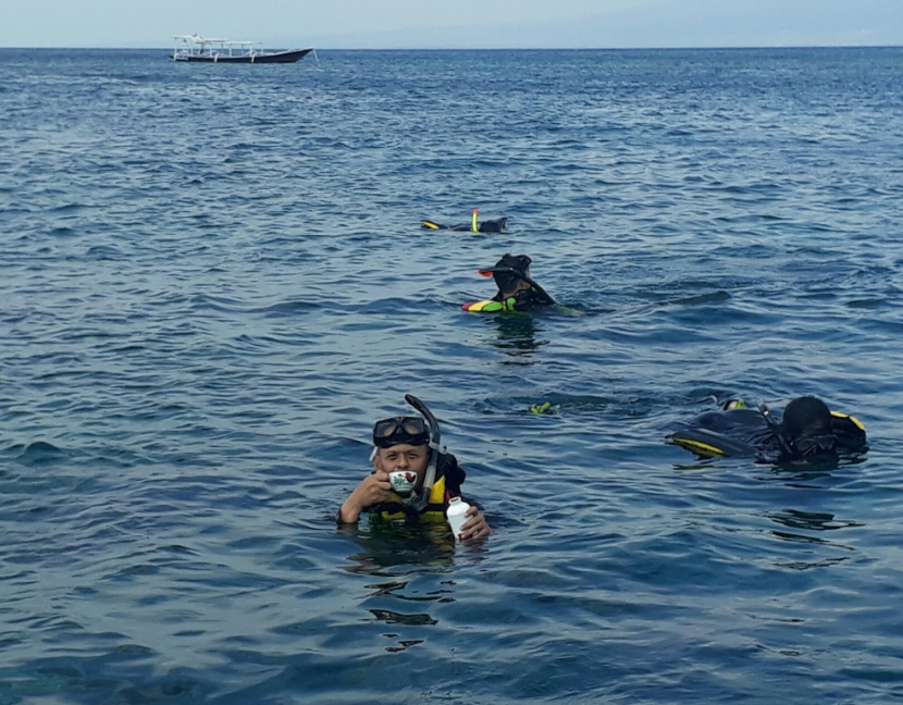 Ngopi dulu seseruput, menghangatkan badan sewaktu snorkeling di pagi hari di perairan Gili Terawangan.