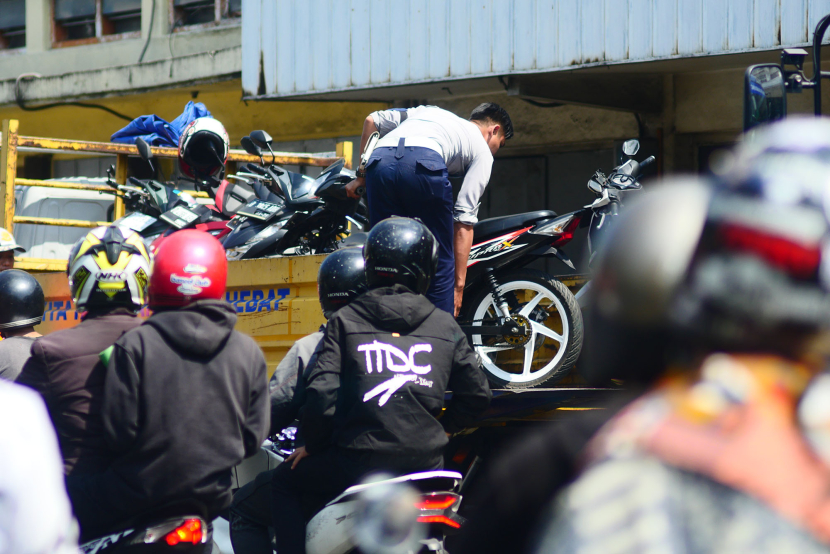 Petugas Dinas Perhubungan sepeda motor yang parkir di tempat terlarang ke atas truk di badan jalan Jl Otto Iskandar Dinata Bandung, Senin (15/7/2024). (Foto: Yogi Ardhi/KangJepret)