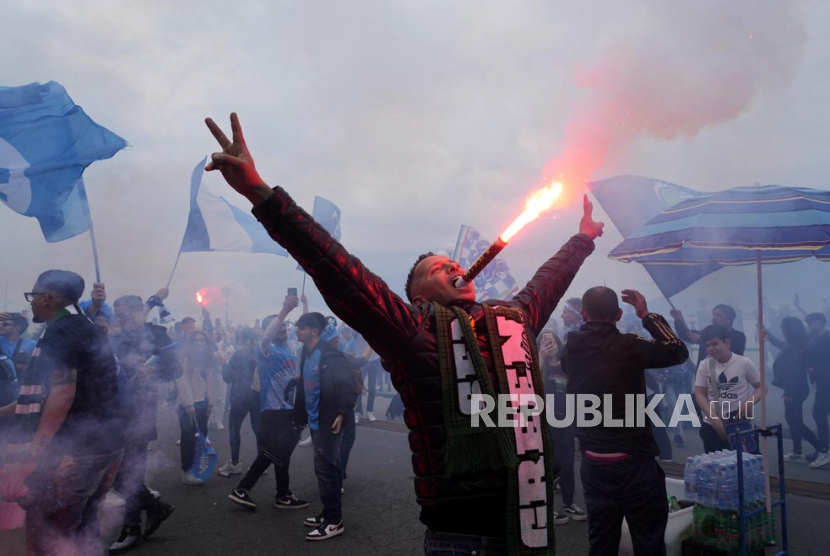 Seorang suporter menaruh hand flare di mulut. Fans Napoli berpesta usai klubnya memastikan juara Serie A Liga Italia musim 2022/2023. Foto: AP Photo/Gregorio Borgia