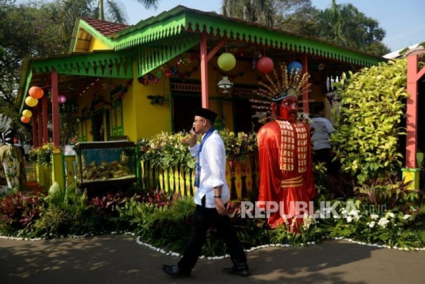 Pengunjung melintas didekat rumah betawi saat acara Lebaran Betawi 2019 di lapangan silang Monumen Nasional (Monas), Jakarta. Asal-usul Nama Betawi: Dari Pelesetan Batavia Hingga Kotoran Manusia. Sumber: Republika/Prayogi