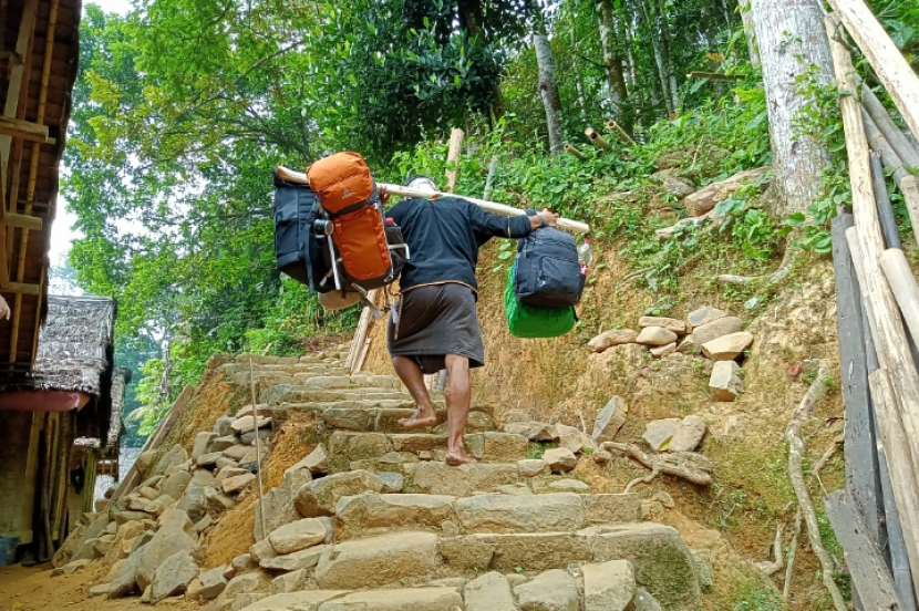 Pemuda Baduy memikul tas pengunjung.