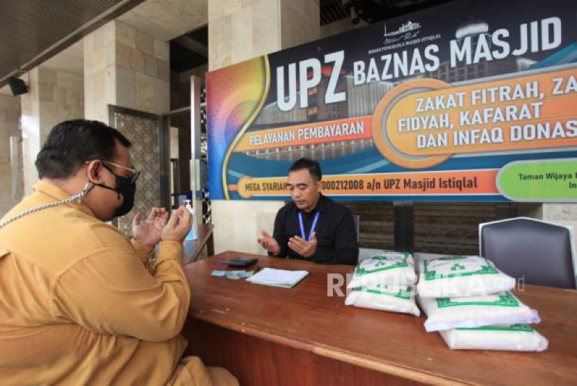 Petugas amil zakat mendoakan seorang umat Islam yang membayar zakat fitrah di Masjid Istiqlal, Jakarta, Kamis, (28/4/2022). Foto: ANTARA/Reno Esnir