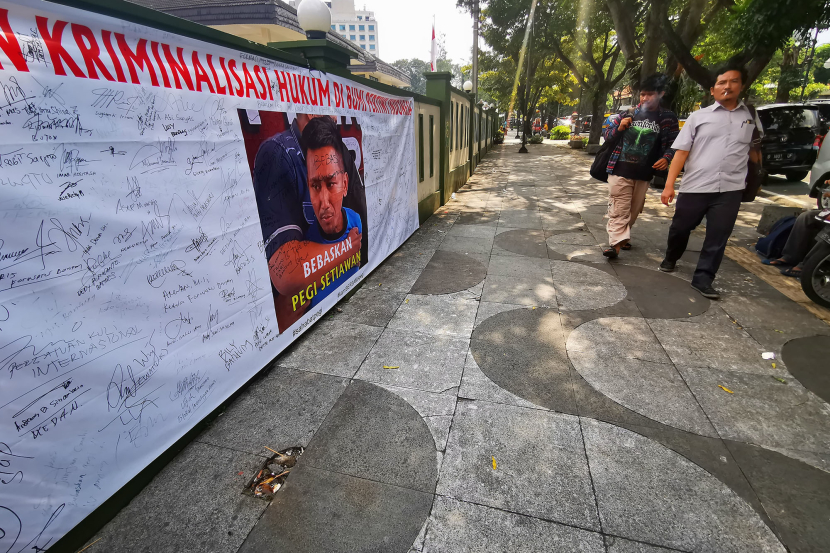 Pejalan kaki melintasi spanduk dan karangan bunga berisi dukungan bagi Pegi Setiawan di depan kantor PN Bandung, Jl Martadinata, Bandung, Senin (8/7/2024).