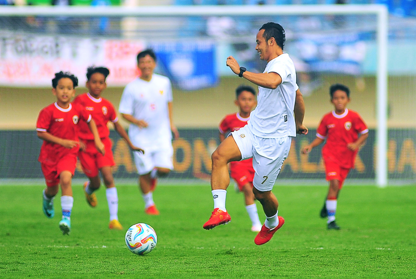 Mantan gelandang serang Persib Bandung menggiring bola dikerubuti puluhan siswa SSB pada laga funsoccer jelang pembukaan Turnamen Piala Presiden 2024 di Stadion Si Jalak Harupat, Kabupaten Bandung, Jumat (19/7/2024). (FOTO: YOGI ARDHI/REPUBLIKA NETWORK) Nikon D3, Nikkor 300/2.8 ED MF.