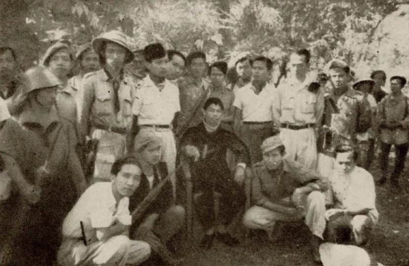 Soeharto berdiri di samping endral Sudirman di markas gerilya. Berjongkok memaka baju dgukung dani celana putih di sebelah kiri adalah Rosihan Anwar. Suparjo Rustam berdiri di samping Jendral Sudirman.