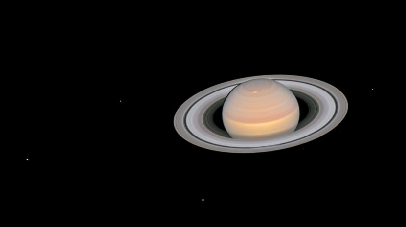 Gambar Saturnus dari Teleskop Antariksa Hubble pada Juni 2018, menunjukkan enam dari 145 bulan bulan yang diketahui. Satelit alami Saturnus yang terlihat adalah bulan Dione, Enceladus, Tethys, Janus, Epimetheus, dan Mimas. Gambar: NASA, ESA, A. Simon (GSFC) dan Tim OPAL, dan J. DePasquale (STScI).