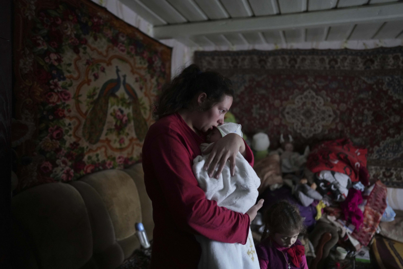 Anastasia Manha (23 tahun) menenangkan bayinya di rumahnya yang disebut terdampak penembakan oleh pasukan separatis pro-Rusia di Novognativka, Ukraina Timur, Ahad (20/2/2022). (AP/Evgeniy Maloletka)