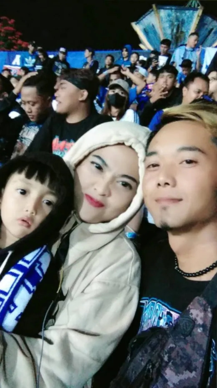 Elmiati duduk di seksi 13 Stadion Kanjuruhan bersama suami dan putranya yang berusia 3 tahun akhir pekan lalu di Malang, Indonesia. 