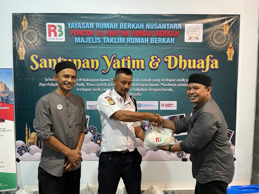 Ketua Yayasan Rumah Berkah Nusantara Juslich Hanafi (kanan) menyerahkan bantuan sembako kepada petugas keamanan saat acara Santunan Yatim dan Dhuafa, pada Ahad (24/4).