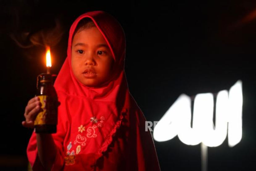 Seorang bocah memegang lampu botol saat merayakan tradisi Tumbilotohe atau malam pasang lampu di Telaga, Kabupaten Gorontalo, Gorontalo, Ahad (9/5/2021). Perayaan malam pasang lampu tersebut dilakukan tiga hari jelang Idul Fitri dan menyambut malam Lailatul Qadar dengan menyalakan lampu minyak di halaman rumah, masjid dan lapangan. Foto: ANTARA FOTO/Adiwinata Solihin