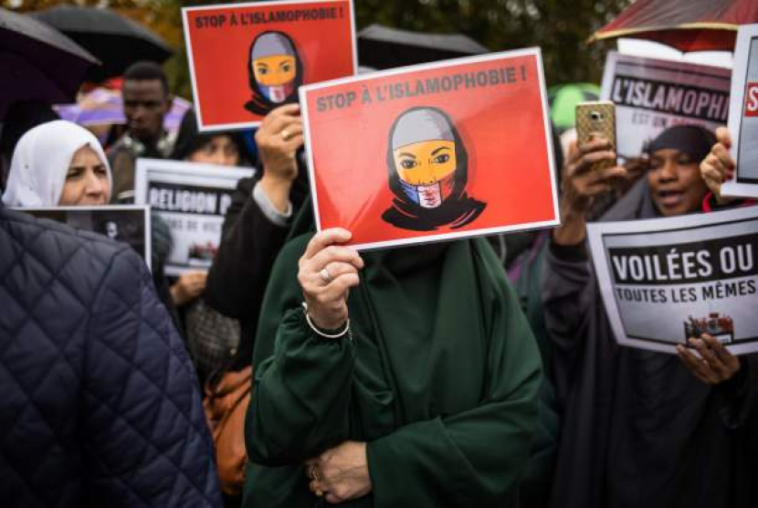 Wanita berjilbab memegang poster bertuliskan 'Hentikan Islamofobia' ketika memprotes Islamofobia di Place de la Nation di Paris, Prancis (27/10/2019) (EPA-EFE/CHRISTOPHE PETIT TESSON/Republika.id)