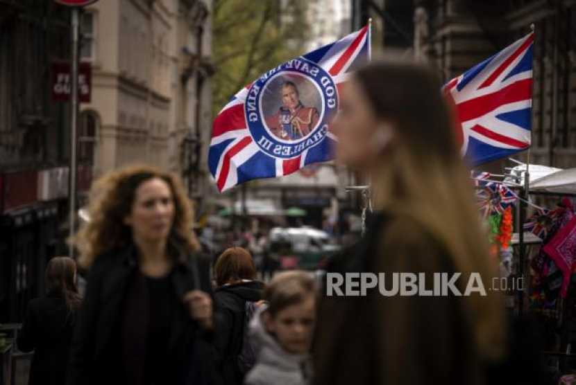 Pejalan kaki melewati kios yang menjual bendera pengumuman Penobatan Raja Charles di London, Jumat, 5 Mei 2023. Penobatan Raja Charles III akan berlangsung di Westminster Abbey pada 6 Mei. Foto: AP Photo/Alessandra Tarantino