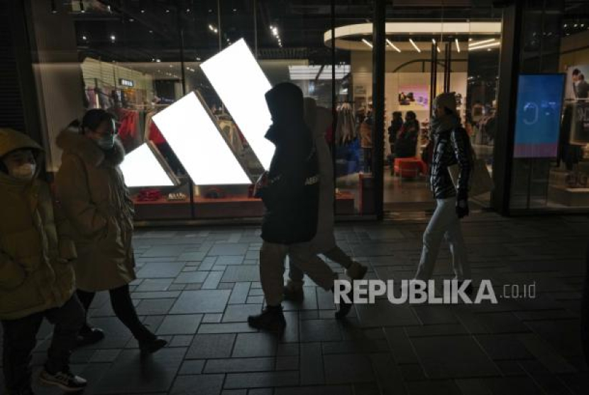 Warga melintasi sebuah toko Adidas di sebuah pusat perbelanjaan di Beijing, Cina, Sabtu (23/12/2023). 