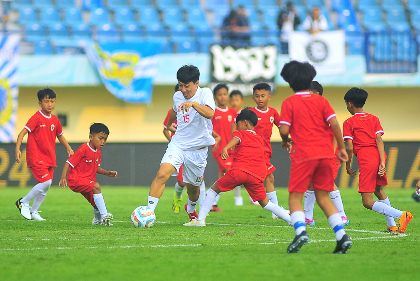 Mantan gelandang Persib Bandung Yaris Riyadi dikerubuti puluhan siswa SSB pada laga funsoccer jelang pembukaan Turnamen Piala Presiden 2024 di Stadion Si Jalak Harupat, Kabupaten Bandung, Jumat (19/7/2024). Bersama lima mantan pemain tim Persib Atep, Zaenal Arief, Robby Darwis, Eka Ramdani, dan Markus Horison melawan 63 siswa SSB se-Bandung Raya. (FOTO: YOGI ARDHI/REPUBLIKA NETWORK) Nikon D3, Nikkor 300/2.8 ED MF.