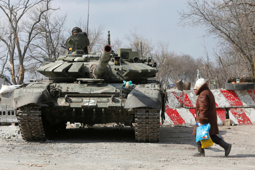 Seorang warga berjalan melewati tank pasukan pro-Rusia di Mariupol. Foto:Alexander Ermochenko/REUTERS