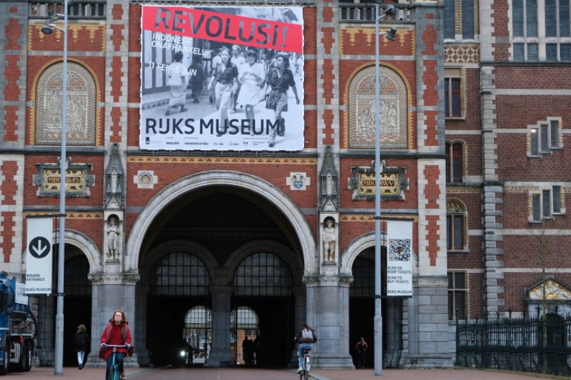 Sebuah spanduk yang mengiklankan pameran kemerdekaan Indonesia tergantung di luar fasad bata merah Rijksmuseum di Amsterdam. Pameran tentang perjuangan kemerdekaan Indonesia dibuka di Rijksmuseum Amsterdam awal bulan ini sebagai bagian dari perhitungan dengan masa lalu kolonialnya yang brutal [Mike Corder/AP Photo