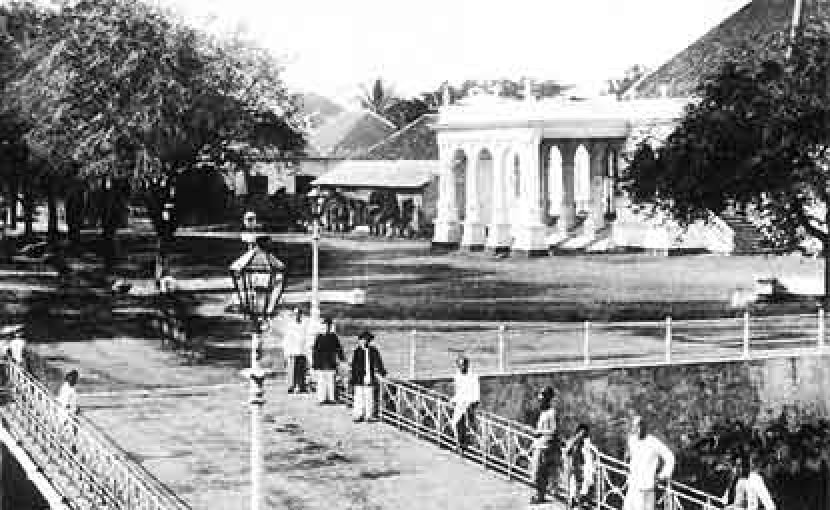 Orang-orang berkumpul di Jembatan Pasar Baru pada tahun 1880. Di samping kanan tampak Gedung Kesenian<a href=