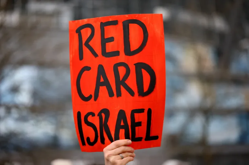 Seorang penggemar sepak bola memegang papan kartu merah di luar Stadion Etihad Manchester City yang menyerukan sanksi terhadap Israel di tengah perang yang terus berlanjut di Gaza [File: Carl Recine/Reuters]