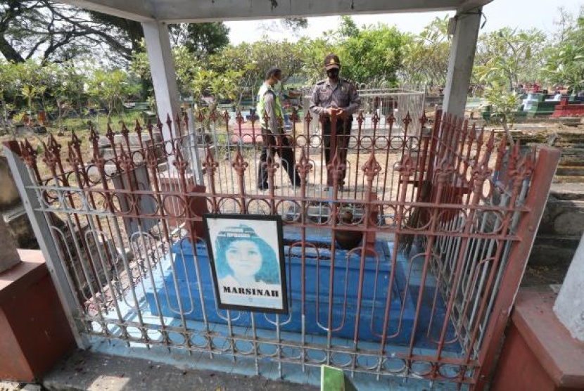 Dua orang anggota polisi berjaga di makam pejuang buruh Marsinah di Desa Nglundo, Nganjuk, Jawa Timur, Sabtu (1/5/2021). Foto: ANTARA/Prasetia Fauzani