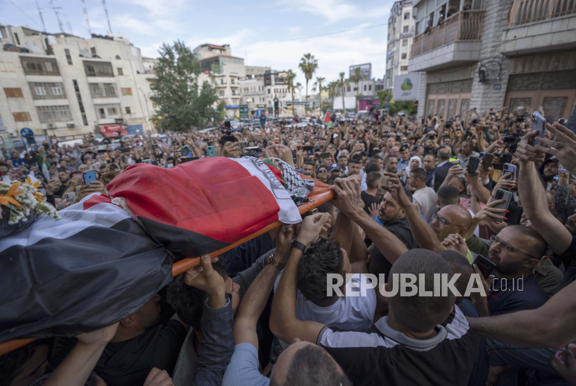 Pelayat Palestina membawa jenazah Shireen Abu Akleh keluar dari kantor Al Jazeera setelah teman dan kolega memberikan penghormatan, di kota Ramallah, Tepi Barat, Palestina, Rabu, 11 Mei 2022. Foto: AP/Nasser Nasser