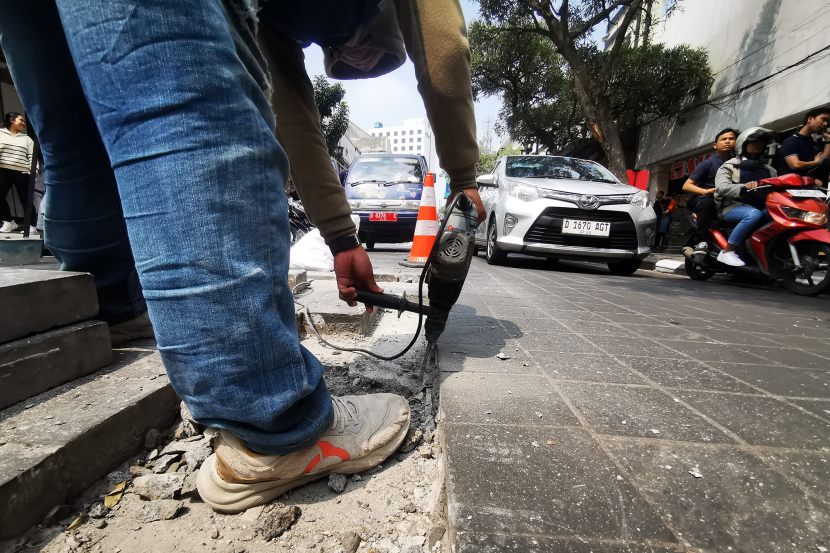 Pekerja membongkar batu andesit yang permukaannya tidak rata di jalan Braga Bandung Rabu (8/5/2024).