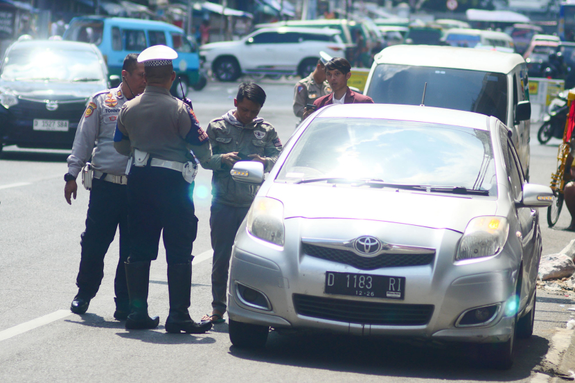 Petugas Dinas Perhubungan dan polisi menindak pengemudi mobil yang memarkirkan mobilnya di badan jalan Jl Otto Iskandar Dinata Bandung, Senin (15/7/2024). (Foto: Yogi Ardhi/KangJepret)