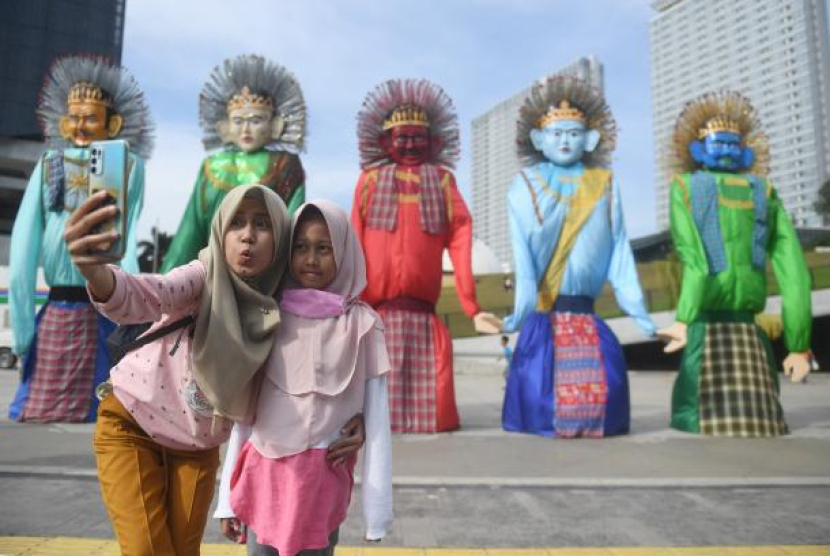 Warga berfoto di instalasi ondel-ondel yang dipamerkan di Taman Ismail Marzuki, Jakarta, Kamis (23/06/2022). Pameran ondel-ondel yang diselenggarakan oleh Majelis Seniman Tim Amir Hamzah tersebut diselenggarakan untuk memeriahkan HUT ke-495 DKI Jakarta. Sumber: ANTARA/Akbar Nugroho Gumay