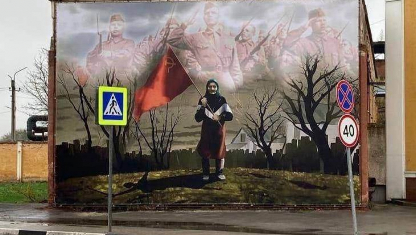 Anna, wanita tua itu, mengibarkan bendera Uni Soviet ketika tentara Ukraina lewat di depannya.